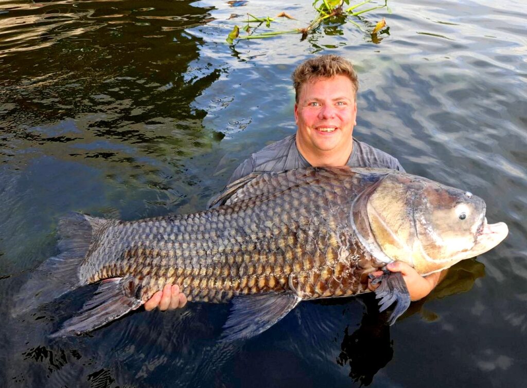 Helge with a giant Thailand carp on a fishing adventure, one of the top adventure things to do in Bangkok.
