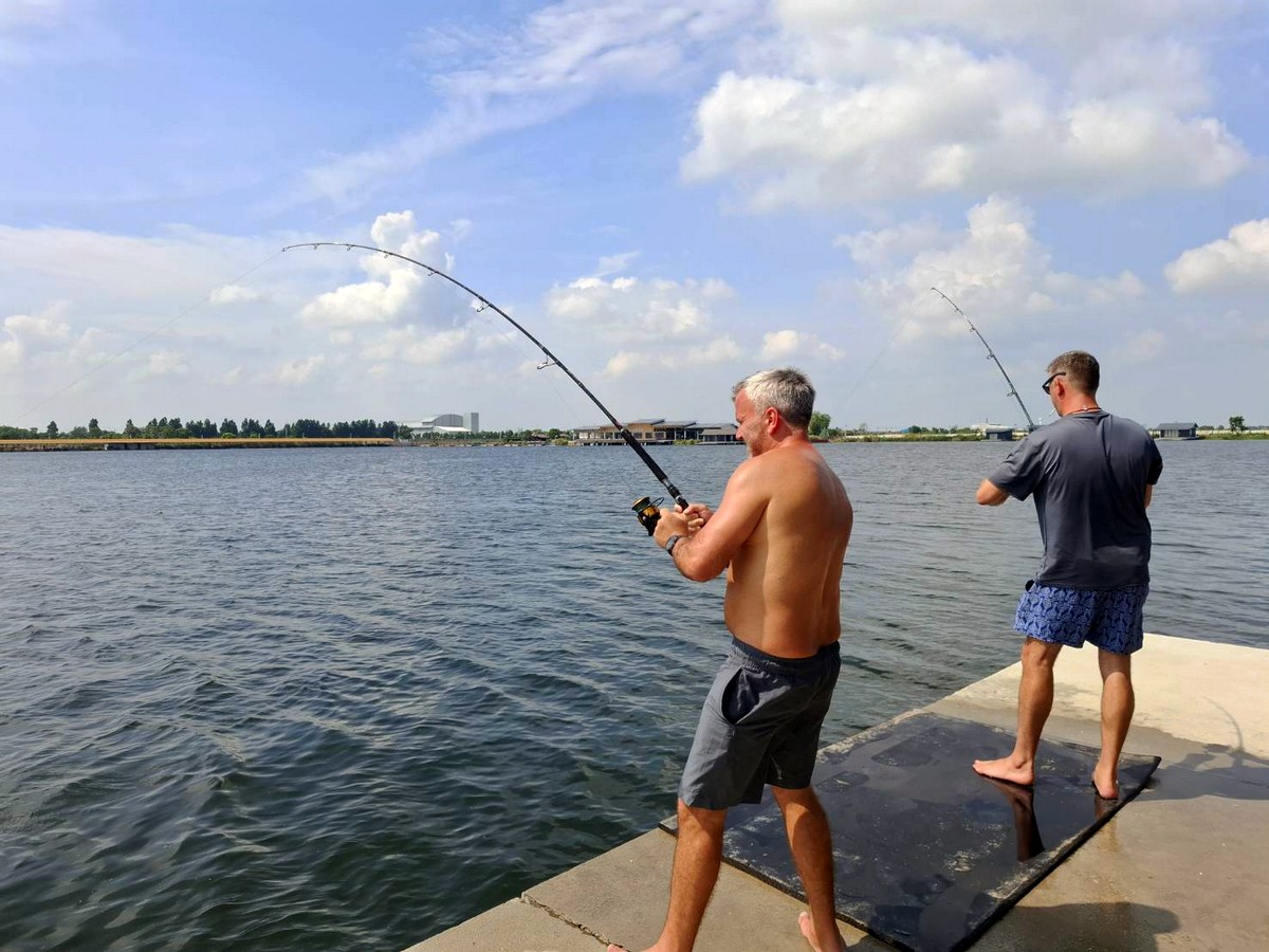 Two anglers playing fish at Bang Len Lake in Thailand